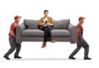 Movers carrying man on couch