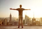 man facing city skyline with arms outstretched
