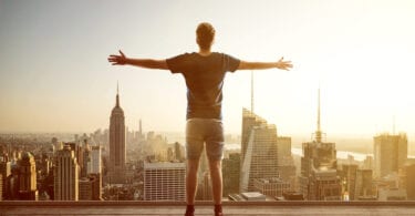 man facing city skyline with arms outstretched