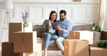 couple with moving boxes using tablet