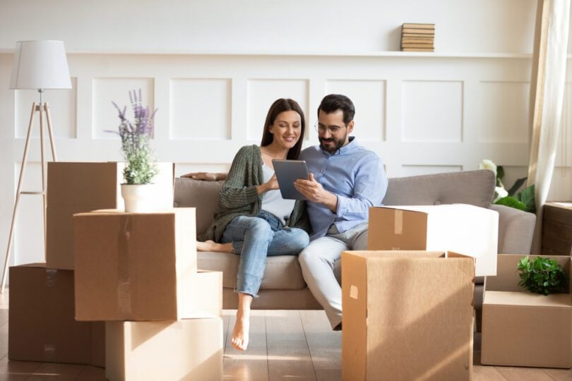 couple with moving boxes using tablet