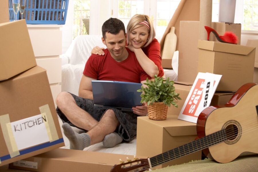 happy couple with computer and moving boxes