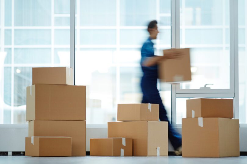blurred photo of mover and stack of moving boxes