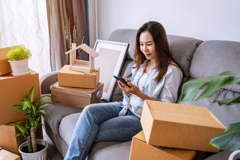 woman with boxes and phone on sofa