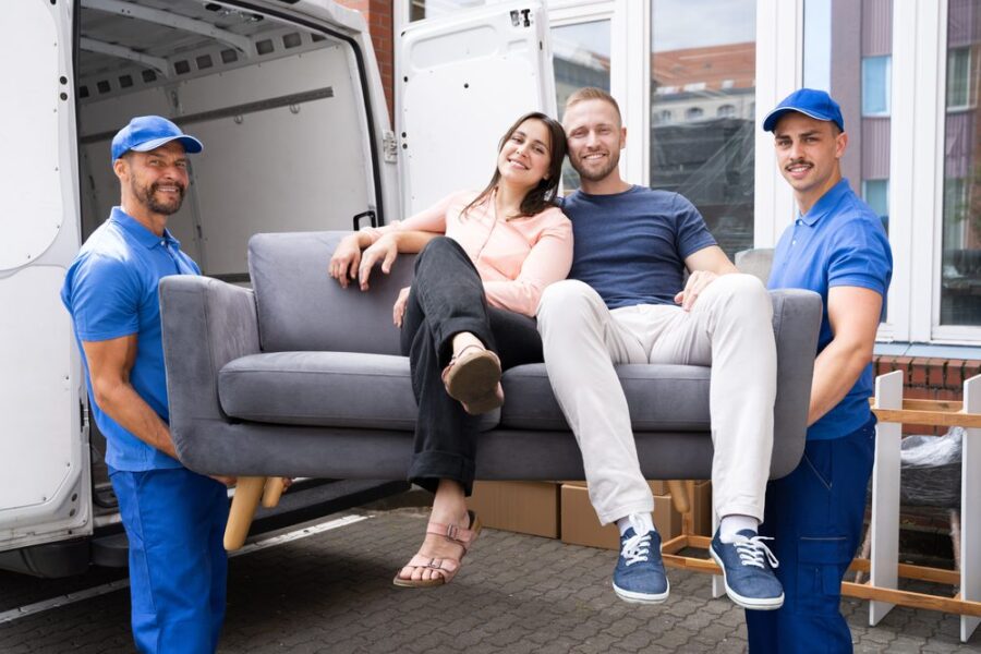 couple sitting on a sofa while the movers carry it
