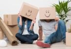 couple wearing boxes with smiling faces on their head