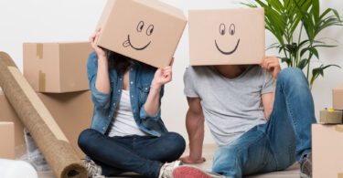 couple wearing boxes with smiling faces on their head