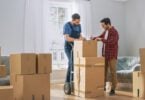 man signing contract with moving company on top of boxes