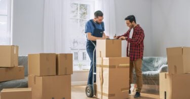 man signing contract with moving company on top of boxes