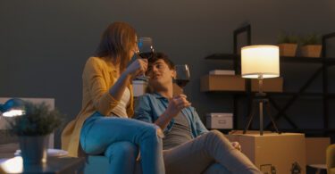 couple toasting with wine surrounded by moving boxes