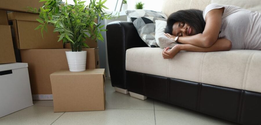 woman asleep on the couch with moving boxes nearby