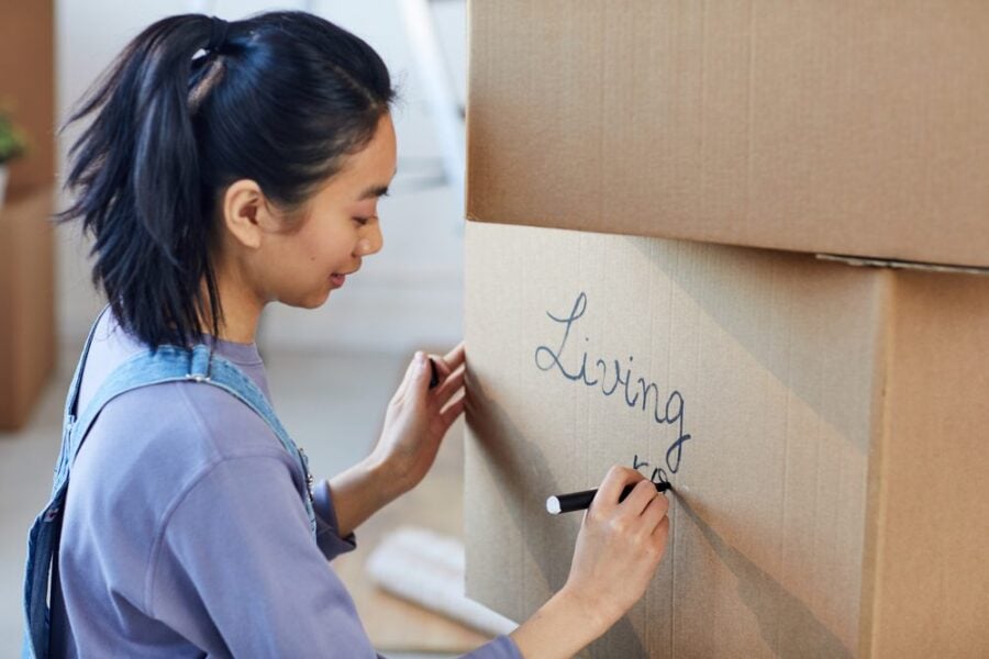 woman labeling moving box with a marker